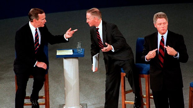 President George H.W. Bush, left, talks with independent candidate Ross Perot as Democratic candidate Bill Clinton stands aside at the end of their second presidential debate in 1992.  