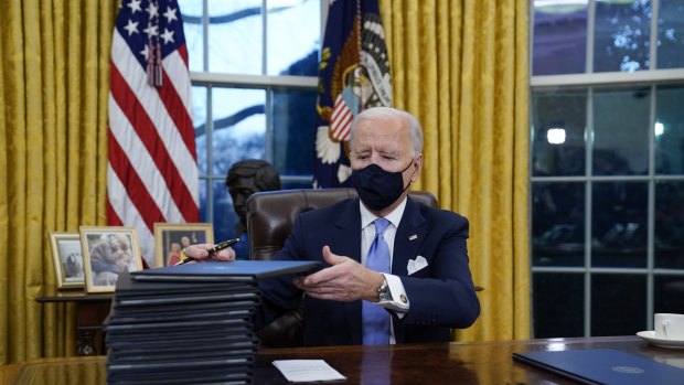 US President Joe Biden signs a flurry of executive orders in the Oval Office on his first day.