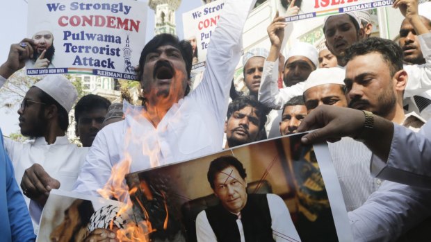 Indian Muslims burn posters of Pakistani Prime Minister Imran Khan, centre, and Hafiz Saeed, chief of Pakistani religious group Jamaat-ud-Dawa, during a protest against an attack on a paramilitary convoy in Kashmir.