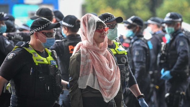 A woman is escorted to be fined at a makeshift police processing point at the United Petrol station on Kings Way on Friday.