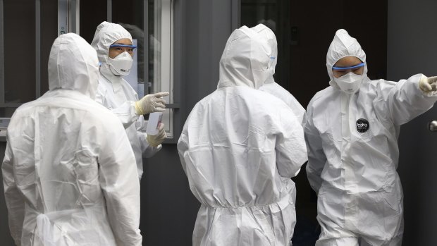 Officials wearing protective attire work to diagnose people with suspected symptoms of the virus in South Korea.