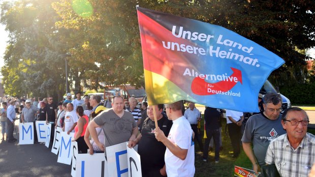AfD supporters hold posters "Merkel must go" and a flag "Our country, our homeland " last year.