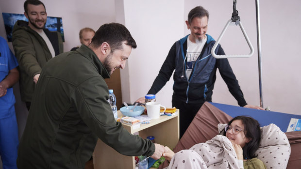 resident Volodymyr Zelenskyy, shakes hands with a wounded Katya Vlasenko , 16, a refugee from Vorzel who covered her junior brother with her body during Russian shelling as they ran from their home town in a hospital in Kyiv, Ukraine. 