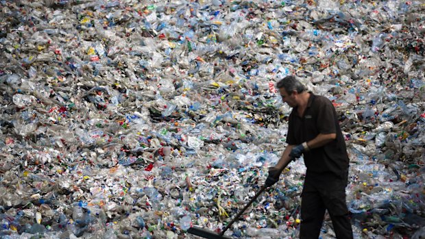 A worker sweeps crushed plastic bottles and containers ahead of sorting in the Netherlands.