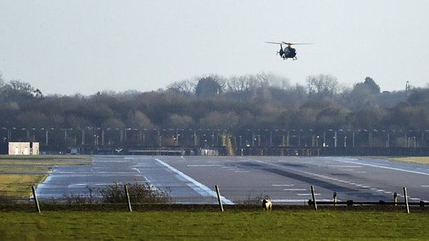 A police helicopter flies over the runway at Gatwick airport.