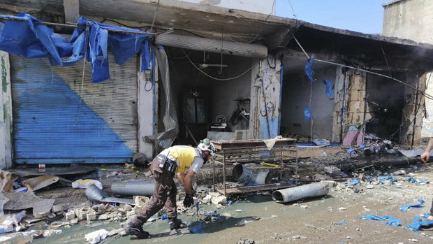 A White Helmet civil defence member works outside damaged shops after shelling hit a street in the town of Ehssem, southern Idlib, on Friday. 