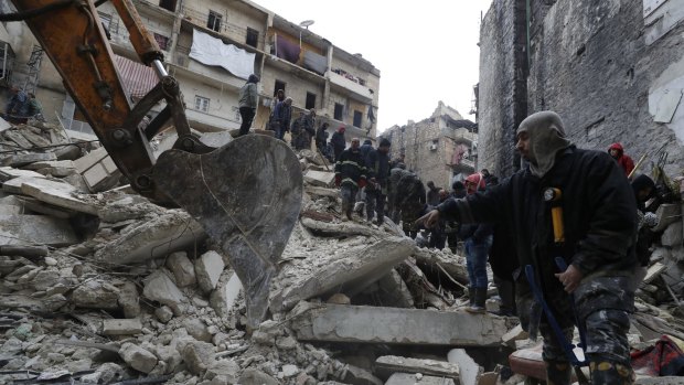 Syrian Civil Defense workers and security forces search through the wreckage of collapsed buildings, in Aleppo, Syria.