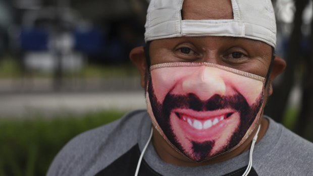 Fabian Santos, a street vendor and supporter of El Salvador’s President Nayib Bukele poses with a Bukele mask outside a vaccination center in San Salvador, El Salvador.