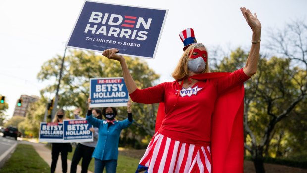 A person dressed in a 'Vote' superhero costume holds a campaign sign for Joe Biden outside a polling station in Atlanta, Georgia, on election day.