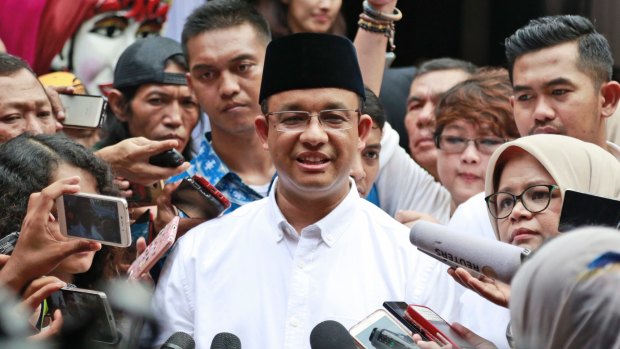 Anies Baswedan, centre, is mobbed by the press after casting his vote in 2017..