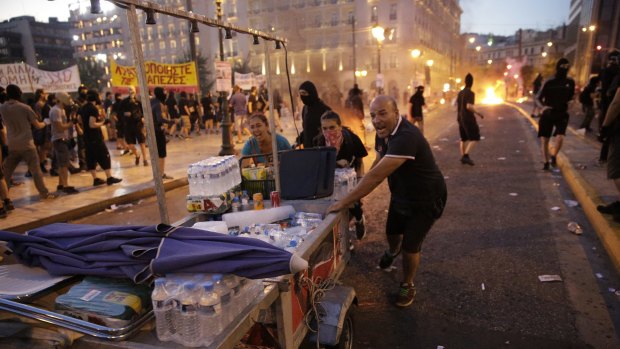 Food vendors rush to clear the area in Syntagma Square during police clashes with protesters in central Athens, Greece, on Wednesday, July 15, 2015. Greek police clashed with protesters in central Athens as lawmakers debated a new bailout of up to 86 billion euros ($94 billion) that will impose further austerity on a country already ravaged by recession. Photographer: Matthew Lloyd/Bloomberg