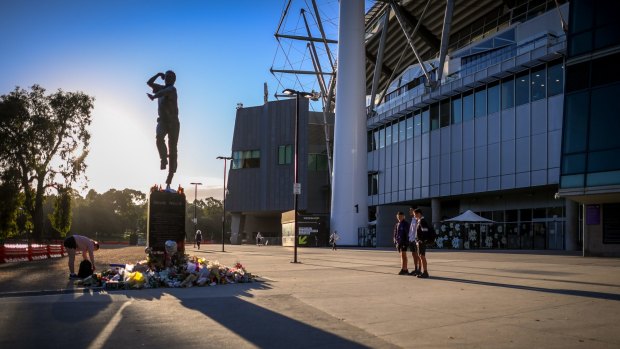People leave tributes at a makeshift memorial at the Shane Warne statue at the MCG.