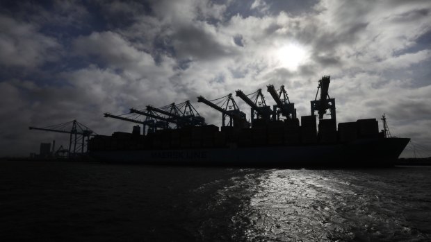 A container ship is silhouetted against the sun as it's unloaded in the harbor of Rotterdam, Netherlands.