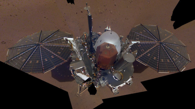 This composite image shows the InSight lander on the surface of Mars. The InSight lander used the camera on its long robotic arm to snap a series of pictures assembled into a selfie. 