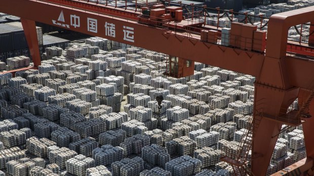 A gantry crane stands as bundles of aluminum ingots sit stacked at a stockyard in Wuxi, China.