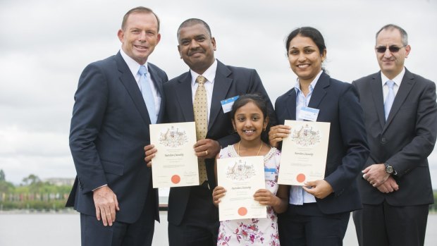 Tony Abbott has his photograph taken in 2015 with a family who took out Australian citizenship after immigrating from India.
