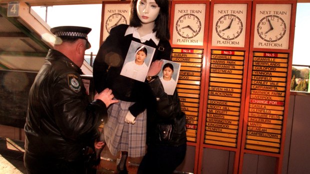 Police hold a mannequin at a train station displaying a photo of Quanne Diec and her school uniform.