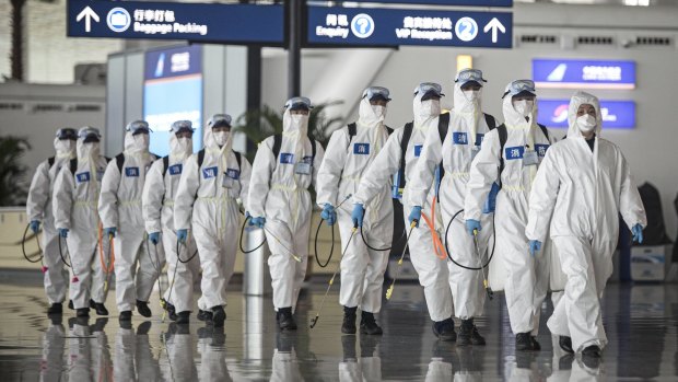 Chinese firefighters in Wuhan, 2020, prepare to disinfect an incoming plane. The Reserve Bank created hundreds of billions of dollars to protect the economy from the pandemic’s impact.