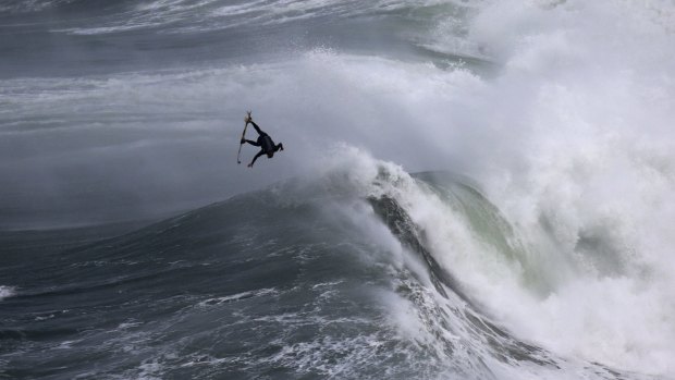 A surfer goes airborne at Praia do Norte, Nazare, Portugal.