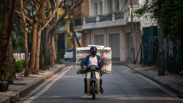 A delivery man with a load of toilet paper rides past the quarantined area of Truc Bach Street in Hanoi, Vietnam. 