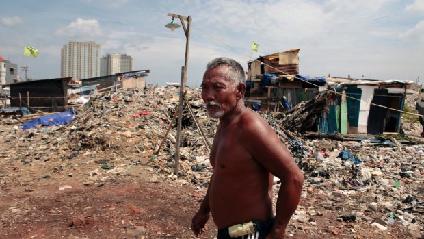 A Kampung Akuarium residents walks through mountains of rubbish and rubble in the makeshift neighbourhood.