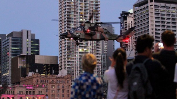 Crowds watch army helicopters fly along the Brisbane River during the 2015 Riverfire.