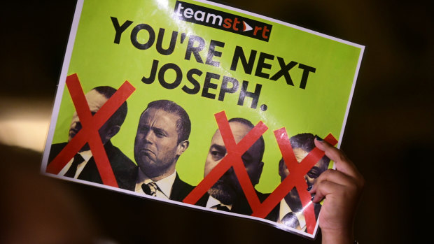 A protester holds up a poster of, from left, former chief of staff to the PM Keith Schembri, Prime Minister Joseph Muscat, Economy Minister Christian Cardona and former tourism minister Konrad Mizzi.