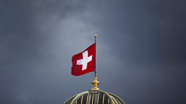 The Swiss flag above Switzerland's parliament building in Bern: The country could be labelled a currency manipulator.