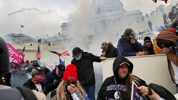 Supporters of U.S. President Donald Trump cover their faces to protect from tear gas during a clash with police officers in front of the U.S. Capitol Building in Washington.