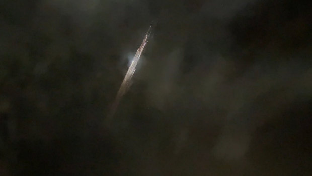 In this image taken from video provided by Roman Puzhlyakov, debris from a SpaceX rocket lights up the sky behind clouds over Vancouver, Washington.