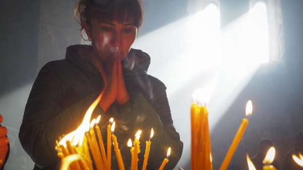 A woman lights candles inside a church of the Dadivank, an Armenian Apostolic Church monastery dating to the 9th century, as ethnic Armenians leave the separatist region of Nagorno-Karabakh to Armenia.