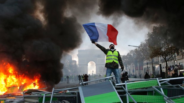 A demonstrator waves the French flag near a burning barricade on the Champs-Elysees on  Saturday.
