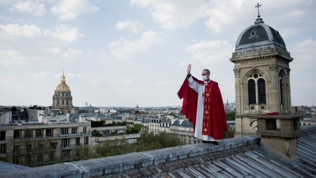 Father Bruno Lefevre Pontalis stands on the rooftop of Saint Francois Xavier church to bless the city of Paris during Easter.
