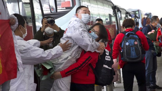 A medical worker, in red, embraces a colleague as she prepares leave Wuhan's main airport on Wednesday.