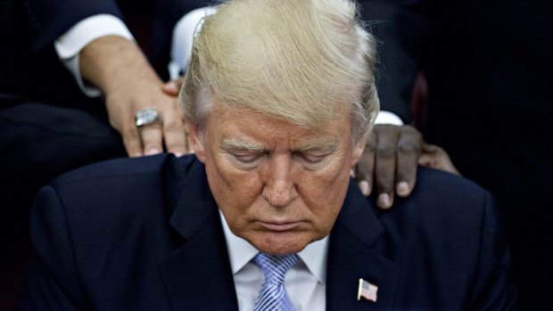 Then-president Donald Trump bows his head during a prayer while surrounded by faith leaders and evangelical ministers after signing a proclamation declaring a day of prayer in the Oval Office in 2017.