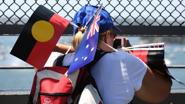Free flags were used as fans and shade as thousands walked around Circular Quay to partake in Australia Day events.