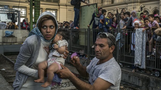 A migrant family gathers with a few hundred others waiting for a train to Germany at the Keleti train station in Budapest, September 2015.