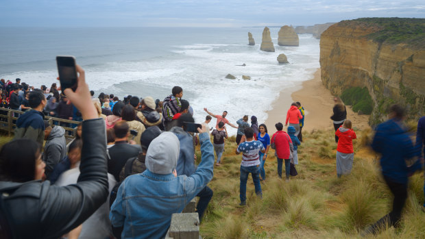 Tourists pose for photos outside the designated viewing area for the Twelve Apostles at Port Campbell weeks ago. 
