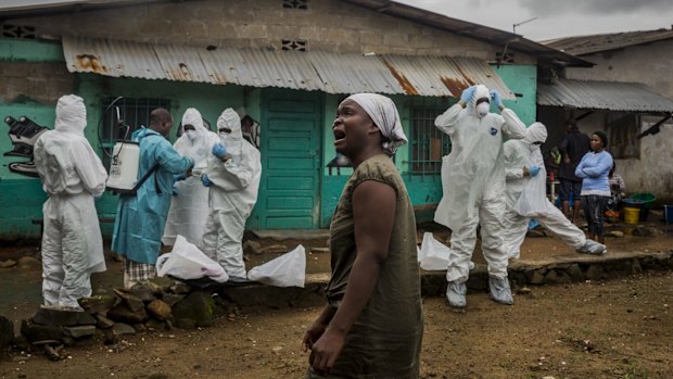 A relative grieves as a Red Cross burial team prepares to remove the body of an Ebola victim in central Monrovia, Liberia.