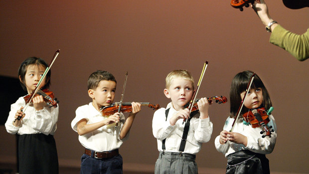 Three-year-old violinists perform in a concert.