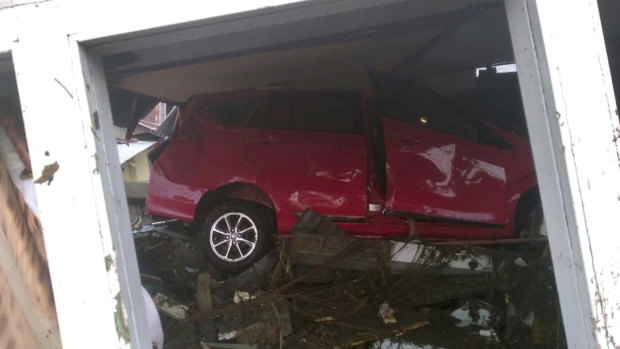 A car swept away by Friday's tsunami is seen stuck under a damaged building in Palu, Central Sulawesi, Indonesia.