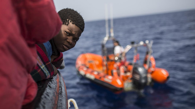 A child rescued from a rubber dinghy off the Libyan coast peers out from aboard the Open Arms aid boat. 