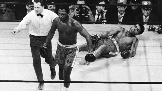 Boxer Joe Frazier being directed to the ropes after knocking down Muhammad Ali during the 15th round of the title bout in Madison Square Garden in New York in 1971.