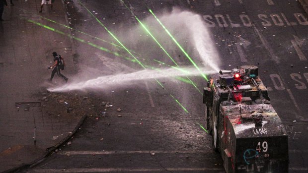 Police water cannon advances on anti-government demonstrators in Santiago, Chile, on Monday. Announced reforms have not yet satisfied protesters who want the President to resign.