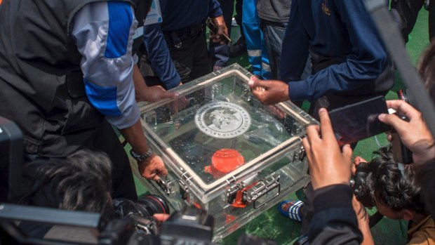 Members of the National Transportation Safety Committee lift a box containing the flight data recorder from the crashed Lion Air jet in November 2018.
