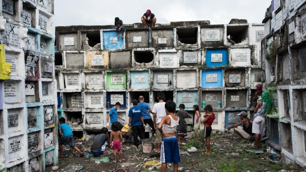 Shanty dwellers living inside the cemetery look at bodies being buried in Manila, Philippines.