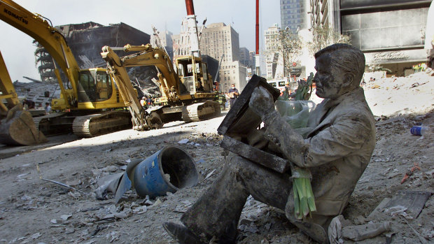 A dust covered bronze statue of a man with his briefcase titled "Double Check," by Seward Johnson, rests in the rubble of the World Trade Centre towers in New York after 9/11.