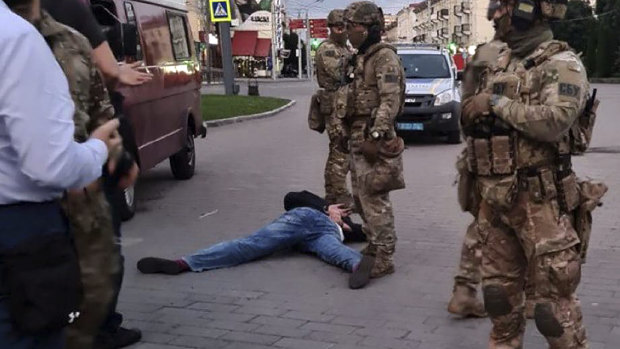 The assailant, who seized a long-distance bus with 10 hostages, lies on the ground after police officers captured him in the city centre of Lutsk.