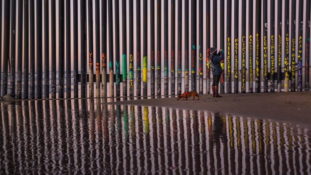 A woman takes a snapshot by the border fence between San Diego, Calif., and Tijuana, as seen from Mexico.