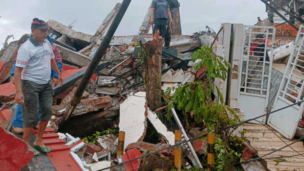 Residents inspect earthquake-damaged houses in Mamuju, West Sulawesi, on Friday.